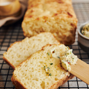 Quiénes somos closeup shot of delicious cheese bread with herb butter on a white table